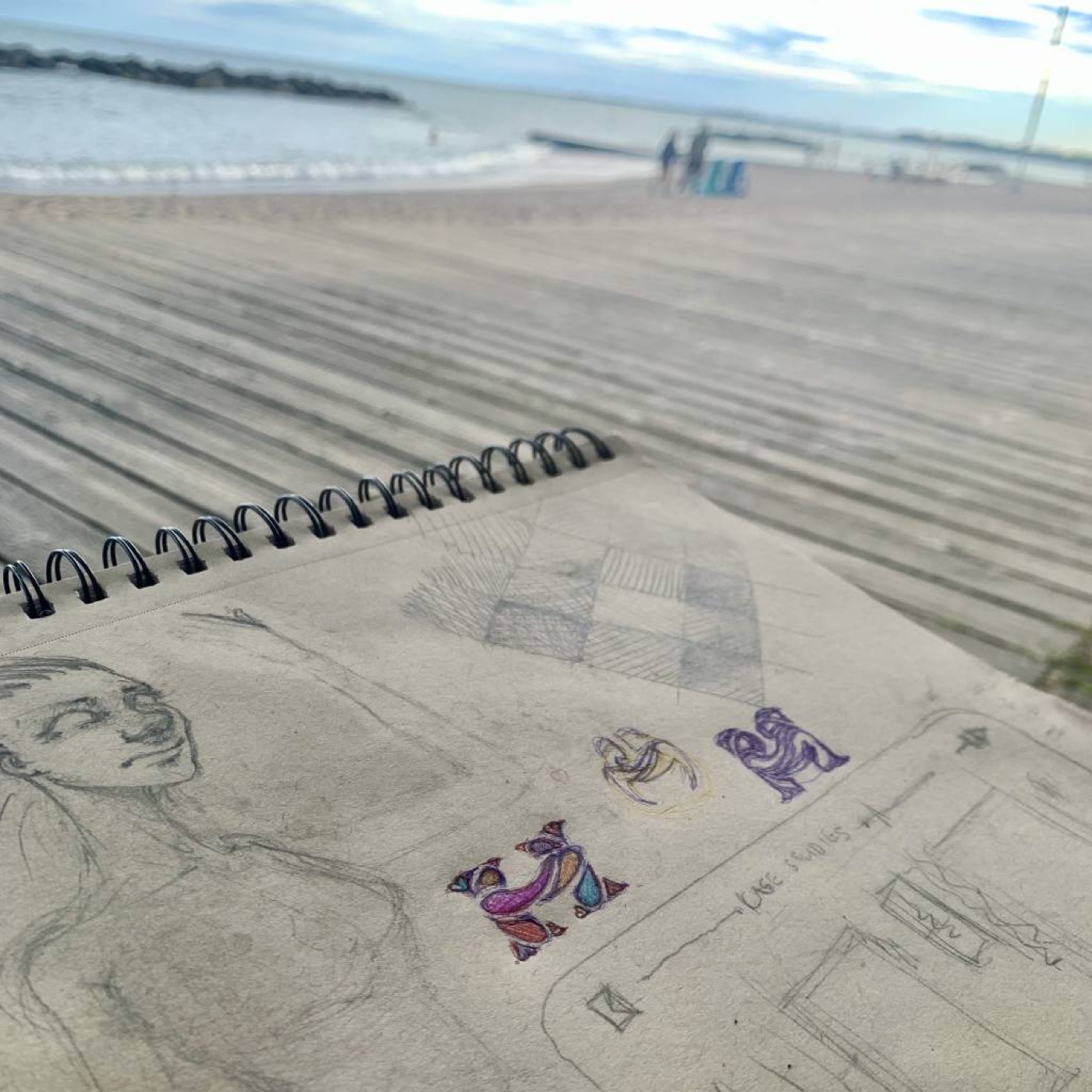 An open sketchbook with the first huddlie mark drawn in crayon among other studies
