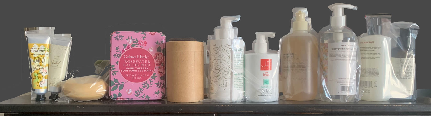 A shelf of product samples: tubes, a soap bar, a tin, a kraft canister and pump bottles